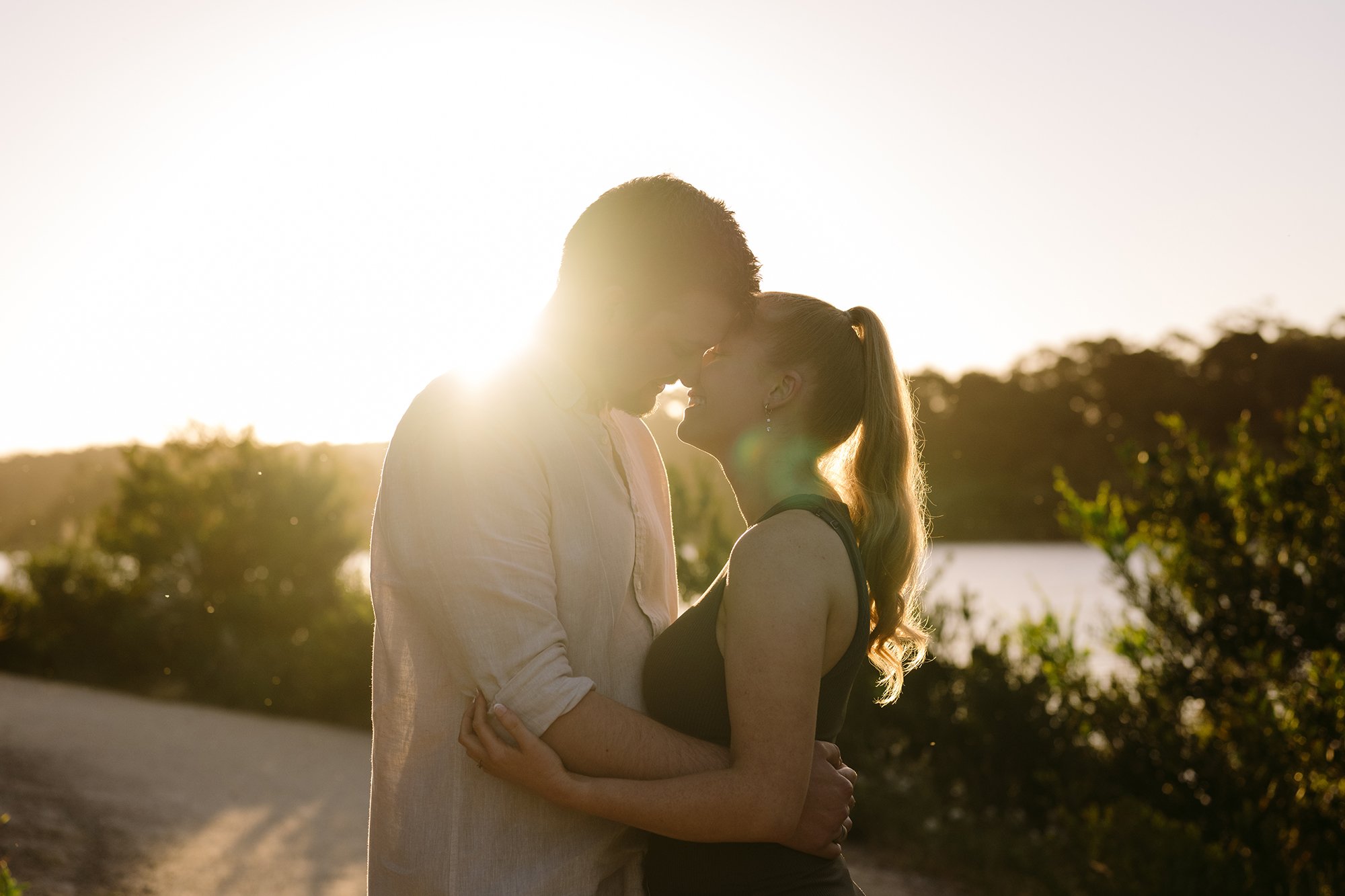 A couple are kissing in front of the sunset at this Mornington Peninsula Engagement Photo location