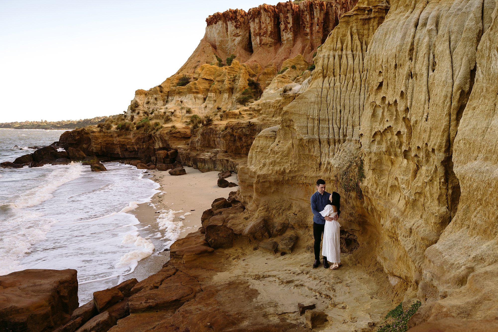 A couple are standing together at the beach photo location
