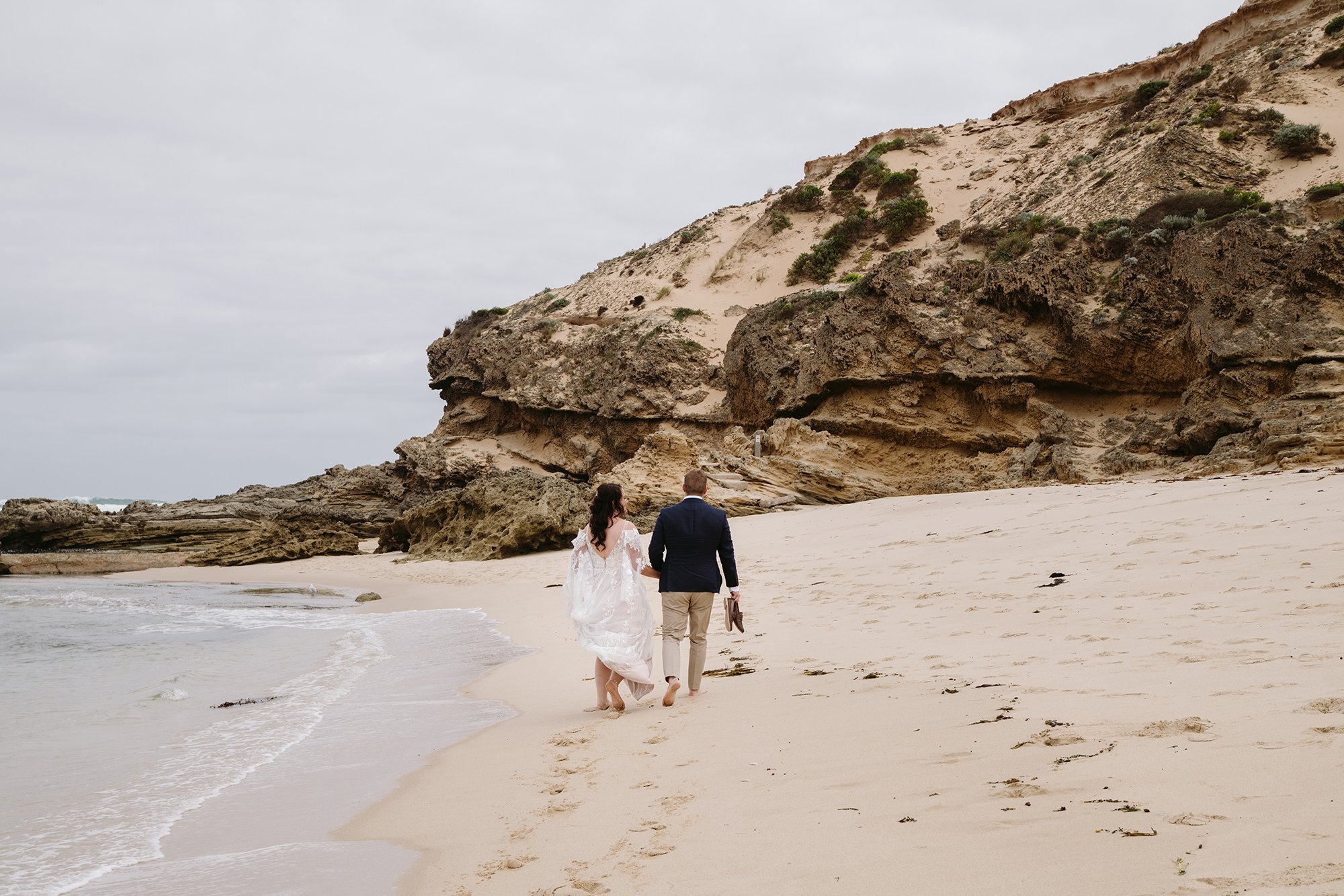 A wedding couple are walking on the beach at this Mornington Peninsula Engagement Photo location