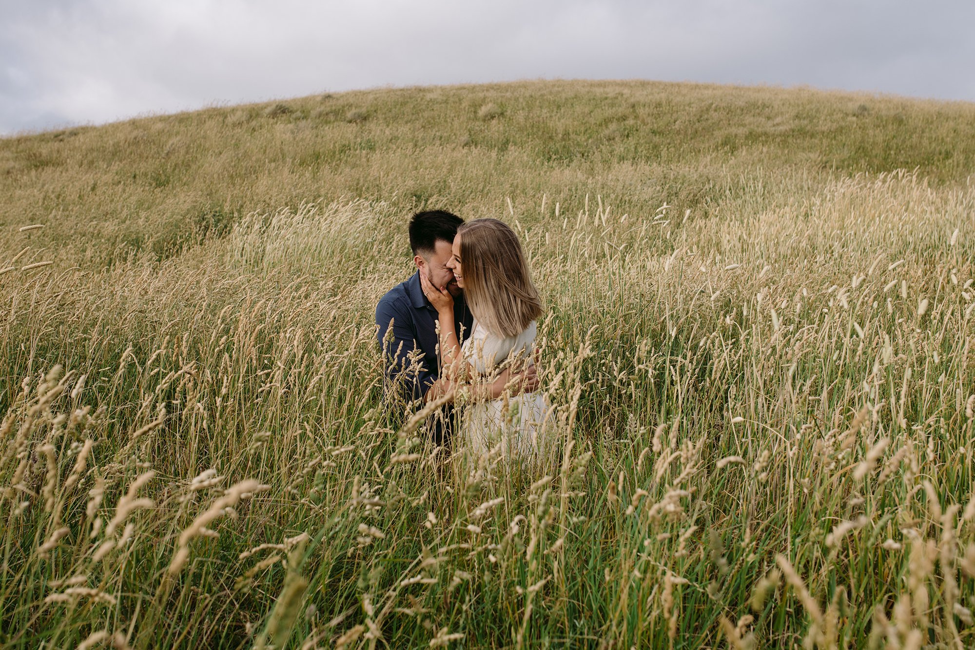 A couple are kissing in long grass 