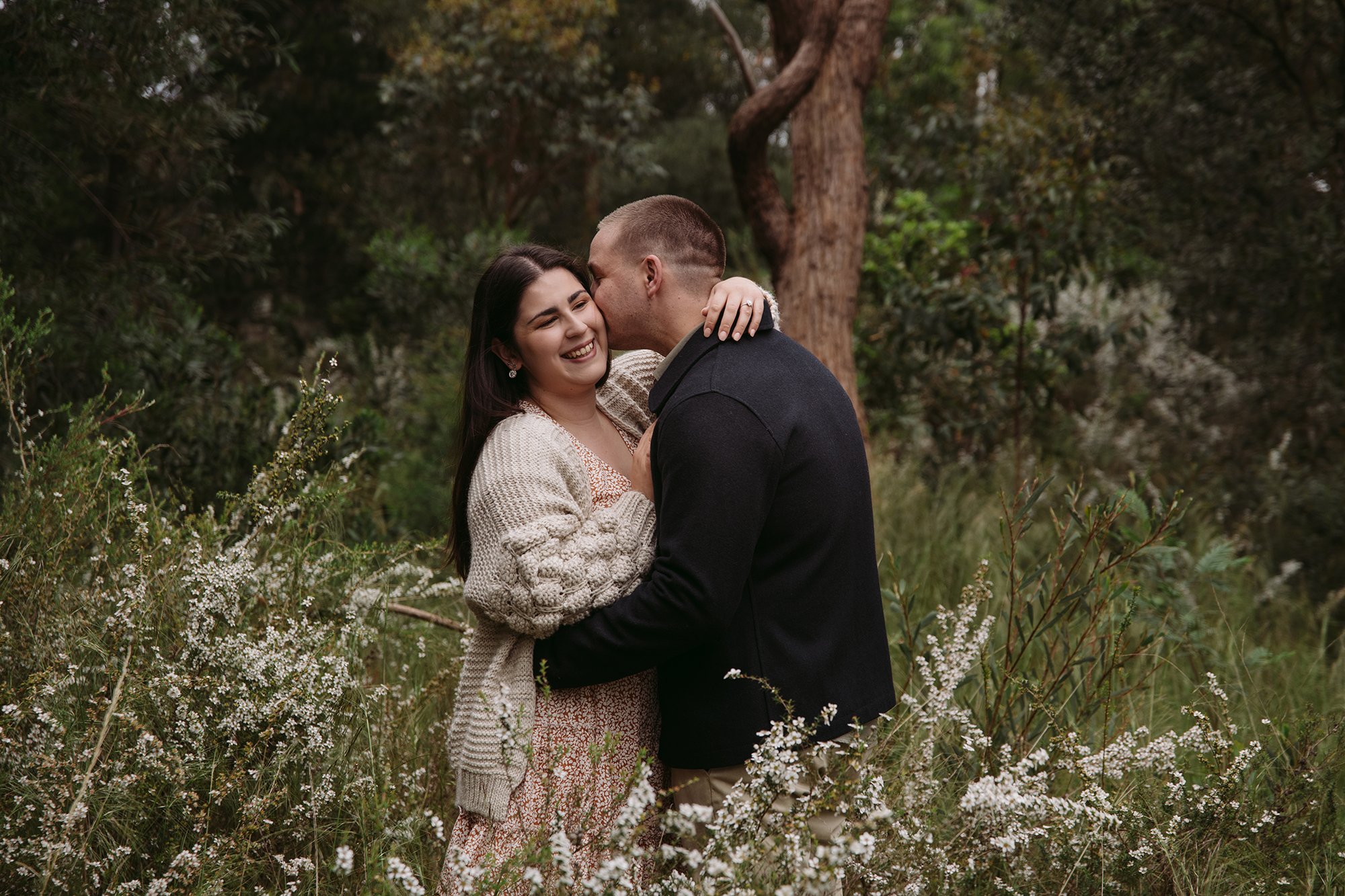 a couple are kissing in the park at this Mornington Peninsula Engagement Photo location